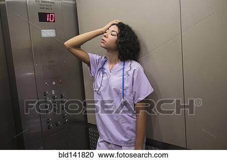 Stressed mixed race nurse standing in elevator View Large Photo Image Stock Image - Stressed mixed race nurse standing in elevator. Fotosearch