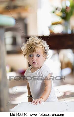 Stock Image - Surprised Caucasian baby boy standing indoors. Fotosearch