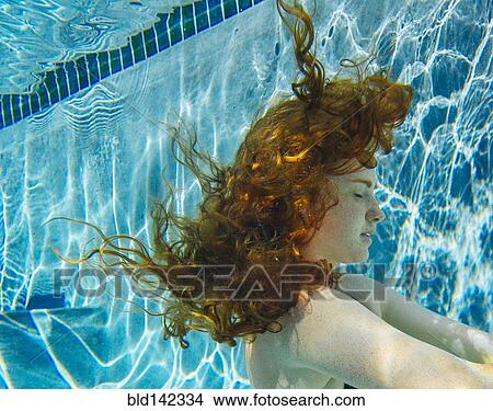 Teenage girl with red hair swimming underwater in pool View Large Photo Image Picture - Teenage girl with red hair swimming underwater in pool. Fotosearch