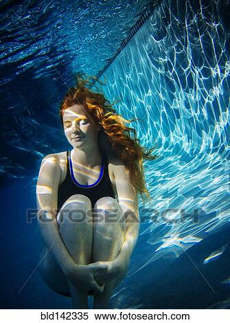 Stock Photography - Teenage girl with red hair swimming underwater in pool. Fotosearch
