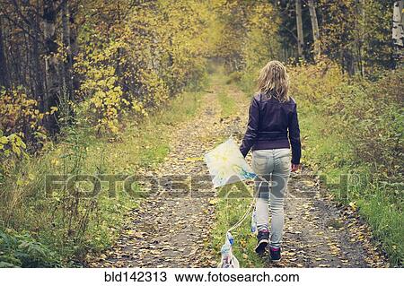 Woman carrying kite on dirt path View Large Photo Image Stock Image - Woman carrying kite on dirt path. Fotosearch