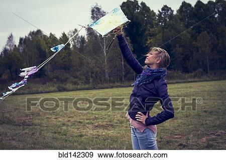 Stock Photo - Woman flying kite in field. Fotosearch
