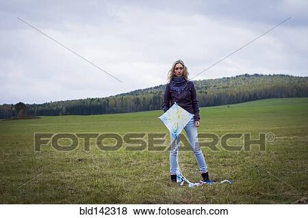 Woman holding kite in field View Large Photo Image Stock Photo - Woman holding kite in field. Fotosearch