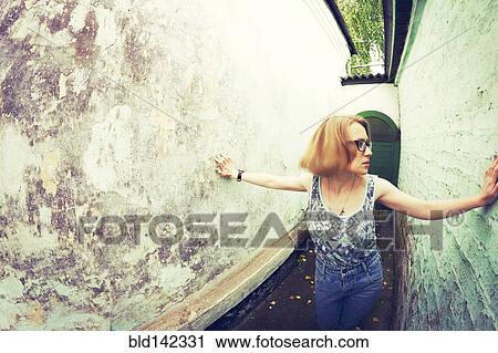Stock Image - Woman touching walls in alley. Fotosearch