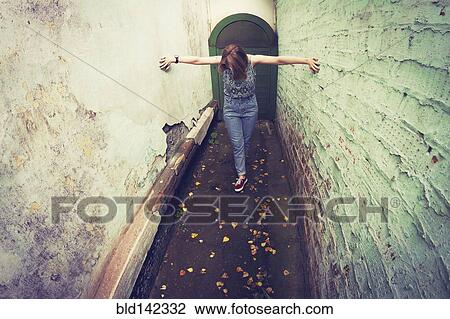 Stock Image - Woman touching walls in alley. Fotosearch