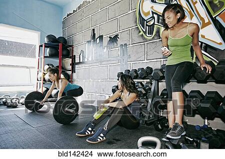 Women watching friend lift weights in gym View Large Photo Image Picture - Women watching friend lift weights in gym. Fotosearch