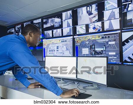 Black security officer watching surveillance cameras View Large Photo Image Picture - Black security officer watching surveillance cameras. Fotosearch