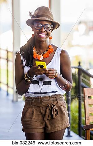 Stock Photograph - Black woman using cell phone outdoors. Fotosearch