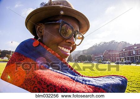 Stock Photograph - Black woman wrapped in blanket in urban park. Fotosearch