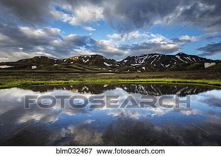 Blue sky and mountains reflected in still remote lake View Large Photo Image Stock Photo - Blue sky and mountains reflected in still remote lake. Fotosearch