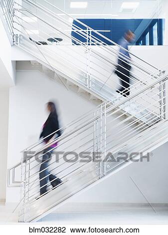 Stock Image - Blurred view of business people climbing office staircase. Fotosearch