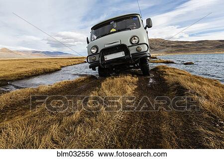 Bus driving through river in remote landscape View Large Photo Image Stock Photograph - Bus driving through river in remote landscape. Fotosearch