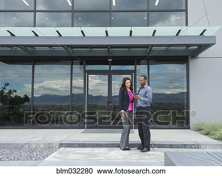 Stock Image - Business people talking outside office building. Fotosearch