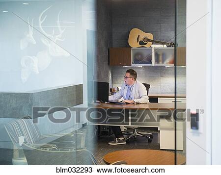Stock Image - Caucasian businessman working at desk in office. Fotosearch