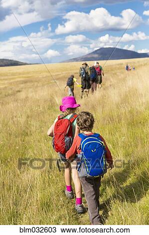 Stock Image - Caucasian children walking in grassy field in remote landscape. Fotosearch