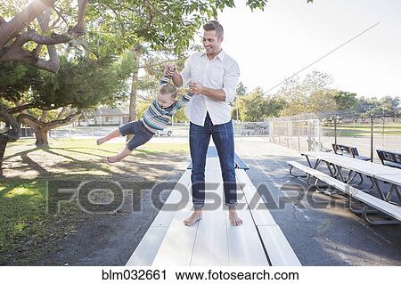 Stock Image - Caucasian father and son playing on picnic table. Fotosearch