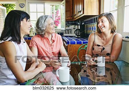 Stock Photography - Caucasian mother and daughters drinking coffee in kitchen. Fotosearch