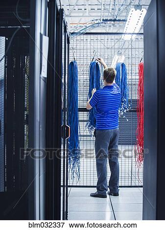 Stock Photo - Caucasian technician hanging cables in server room. Fotosearch