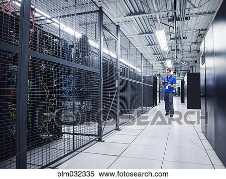 Stock Photography - Caucasian technician using digital tablet in server room. Fotosearch