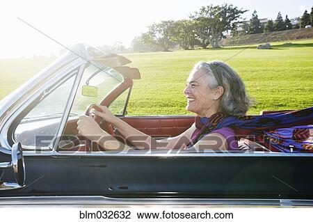 Stock Image - Caucasian woman driving classic convertible. Fotosearch