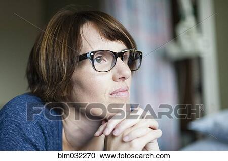 Stock Image - Caucasian woman thinking with hands clasped. Fotosearch