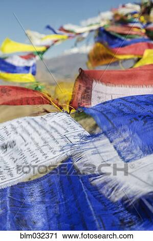 Stock Image - Close up of colorful prayer flags blowing in breeze. Fotosearch