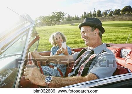 Stock Photograph - Couple taking cell phone photograph in classic convertible. Fotosearch