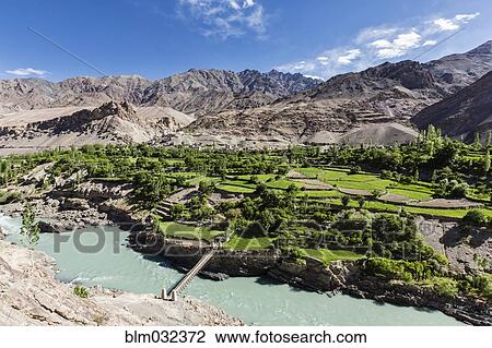 Stock Image - High angle view of houses and pastures in mountain valley. Fotosearch
