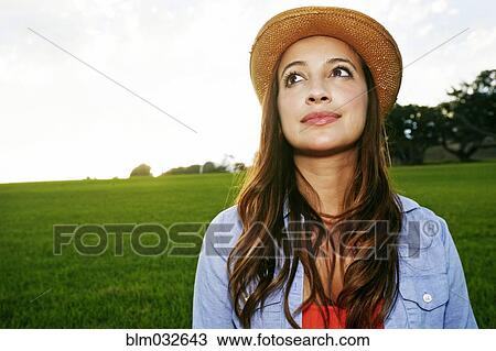 Stock Image - Hispanic woman smiling in grassy field. Fotosearch