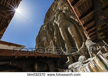 Low angle view of carved Buddha statue in rock wall View Large Photo Image Stock Image - Low angle view of carved Buddha statue in rock wall. Fotosearch