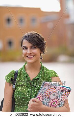 Mixed race student carrying books on campus View Large Photo Image Stock Image - Mixed race student carrying books on campus. Fotosearch