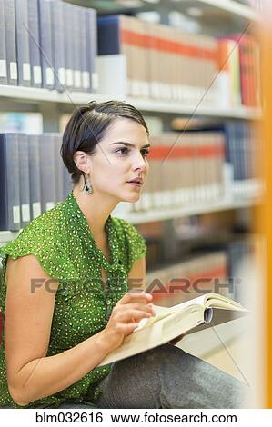 Stock Photograph - Mixed race student reading book in library. Fotosearch