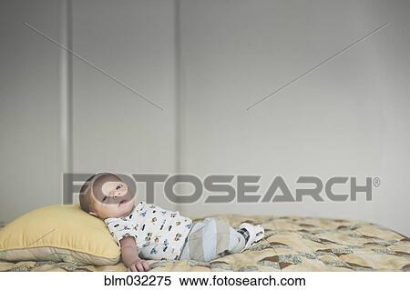 Stock Photography - Newborn mixed race baby laying on bed. Fotosearch