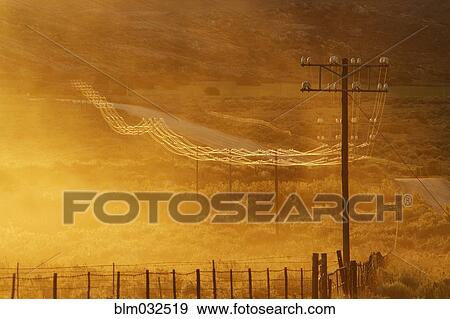 Stock Photo - Power lines on road in grassy remote landscape. Fotosearch