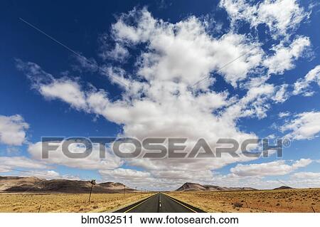 Stock Image - Remote road under blue sky in desert landscape. Fotosearch