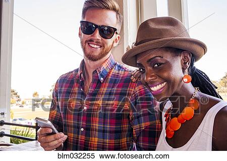Stock Photography - Smiling couple using cell phone together. Fotosearch