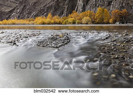 Stock Image - Time lapse view of river and rocky riverbed in remote landscape. Fotosearch