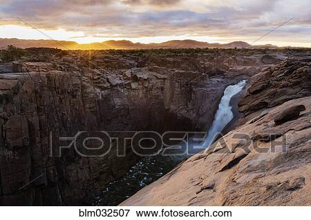 Waterfall flowing over rocky cliffs in remote landscape View Large Photo Image Stock Photo - Waterfall flowing over rocky cliffs in remote landscape. Fotosearch