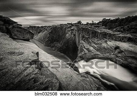 Stock Photo - Waterfall flowing over rocky cliffs in remote landscape. Fotosearch