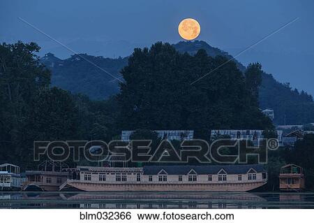 Yellow moon over hills and floating houseboats View Large Photo Image Stock Photograph - Yellow moon over hills and floating houseboats. Fotosearch