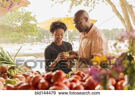 Stock Photo - African American couple browsing produce in farmers market. Fotosearch