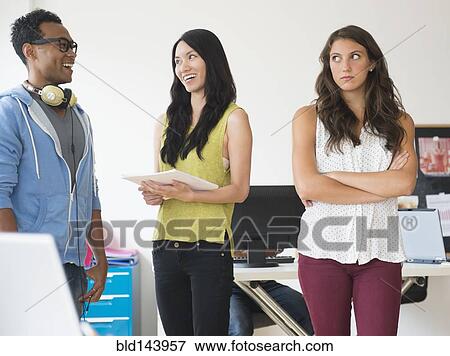 Annoyed businesswoman ignoring colleagues in office View Large Photo Image Stock Photo - Annoyed businesswoman ignoring colleagues in office. Fotosearch
