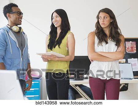 Stock Photo - Annoyed businesswoman ignoring colleagues in office. Fotosearch