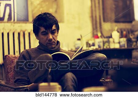 Stock Photo - Asian man reading in armchair. Fotosearch