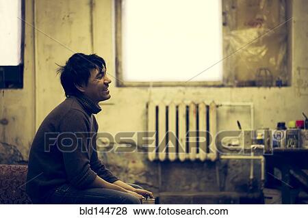Stock Photo - Asian man sitting in bedroom. Fotosearch