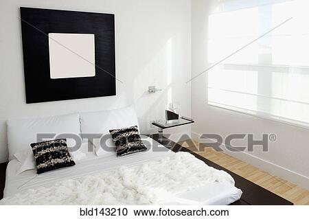 Stock Image - Bed, mirror and window in modern bedroom. Fotosearch