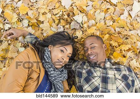 Black couple laying together in autumn leaves View Large Photo Image Stock Photo - Black couple laying together in autumn leaves. Fotosearch