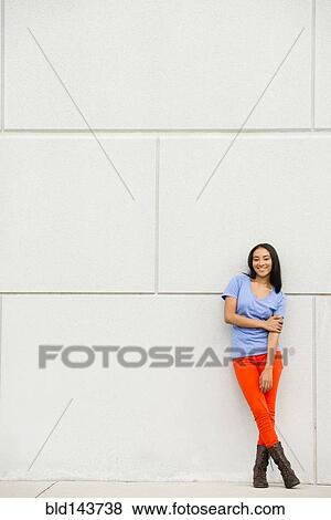 Stock Photo - Black woman smiling near concrete wall. Fotosearch