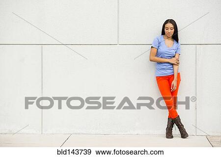 Stock Photo - Black woman standing near concrete wall. Fotosearch