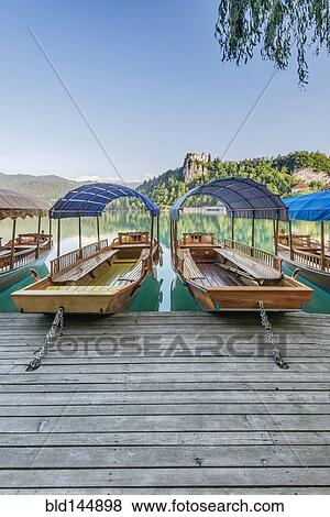 Stock Photo - Boats parked on wooden dock on lake. Fotosearch